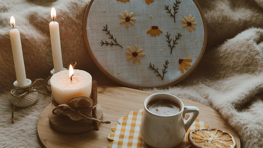 “Cozy embroidery scene with hand-stitched flowers, candles, and hot cocoa — embroidery as a relaxing mindful hobby.”