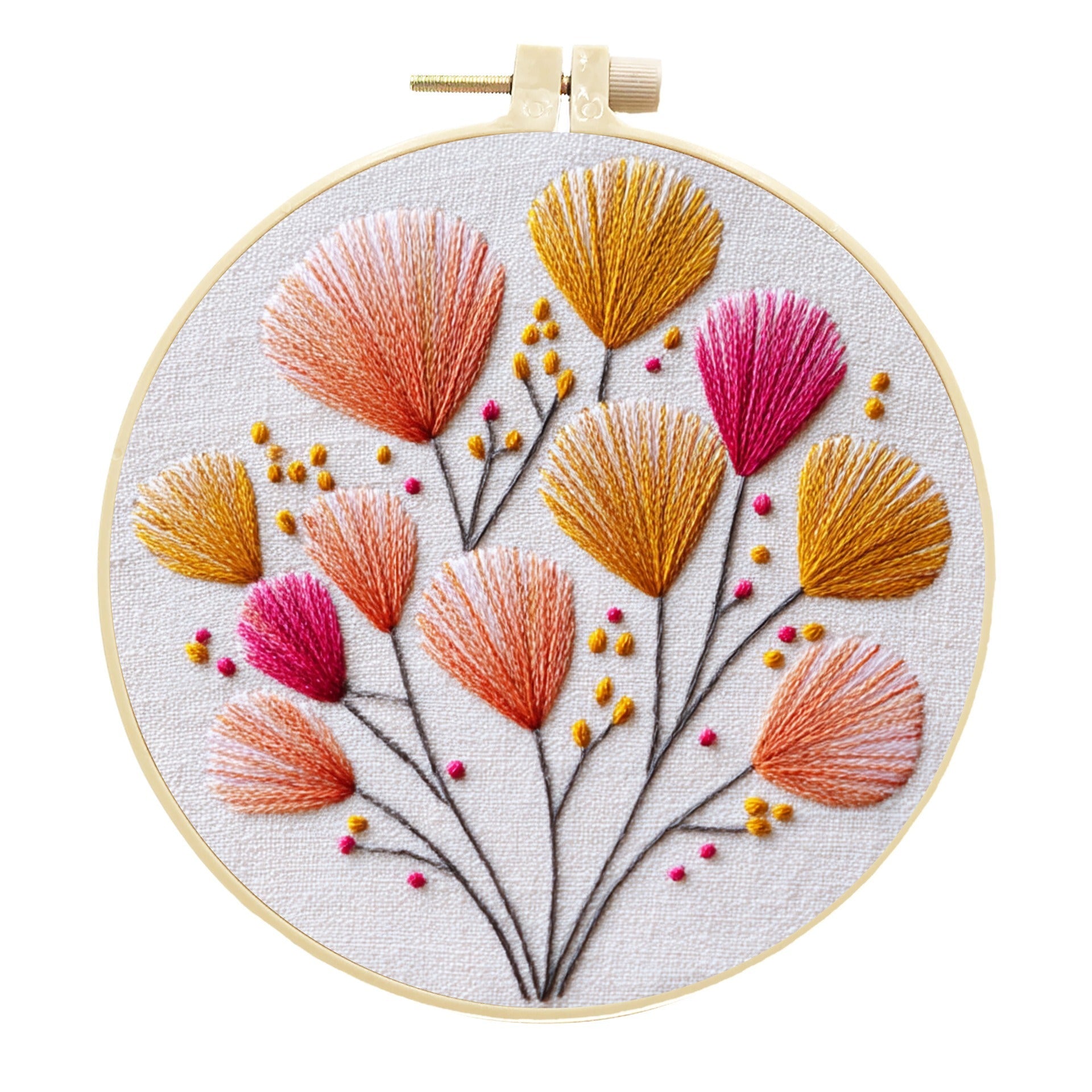 A circular embroidery hoop holding a floral needlepoint or embroidery design on white fabric. The design features stylized flowers in orange, pink, and mustard yellow with thin dark stems and small berry-like accents, photographed against a plain white background.