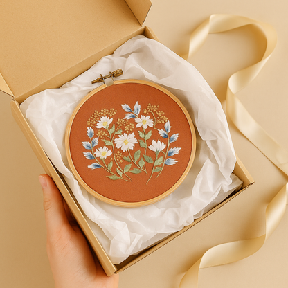 Embroidery kit in a gift box with tissue paper and ribbon, featuring a stitched floral hoop design — ideal for gifting.