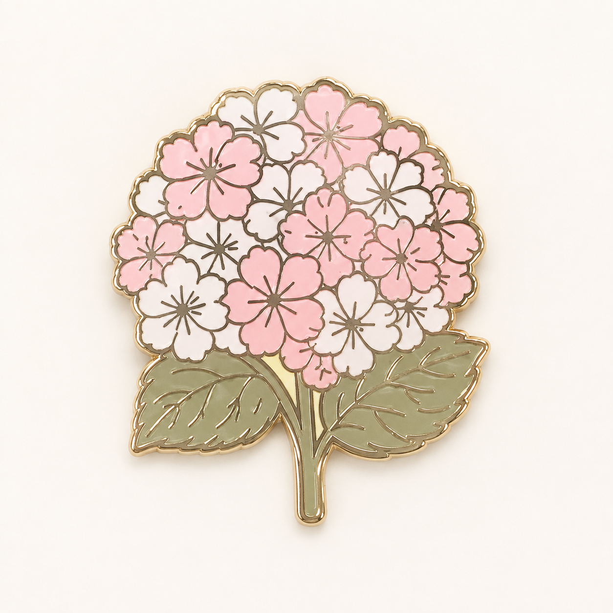A floral enamel pin shaped like a hydrangea with pink and white blossoms and olive green leaves, outlined in gold metal, shown on a plain off-white background.