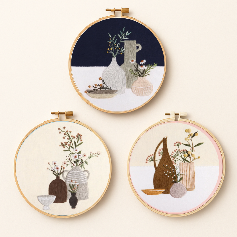 Three embroidery designs of vases and flowers